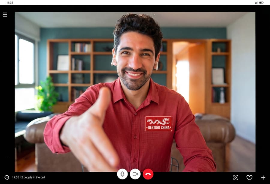 Captura de pantalla de una videoconferencia que muestra a un sonriente asesor de viajes de "Destino China" ofreciendo un apretón de manos virtual, en el contexto de la imagen